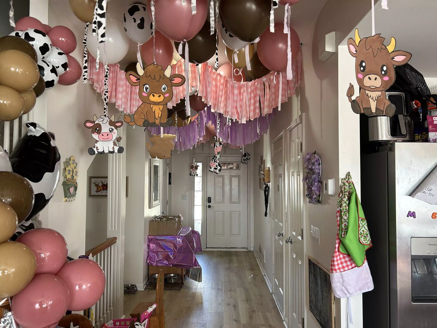 Hallway styled floor to ceiling with pink and brown balloons, tassel garland and cow themed foil balloons overhead