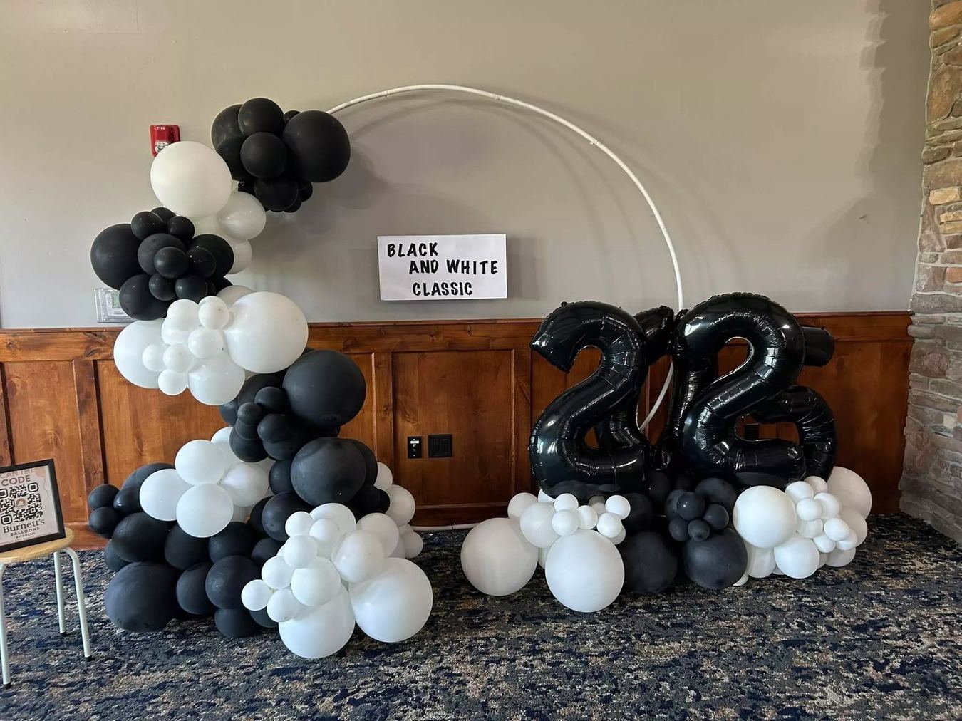 Black and white balloon hoop arch with an oversized foil number 23 beside a Black and White Classic sign