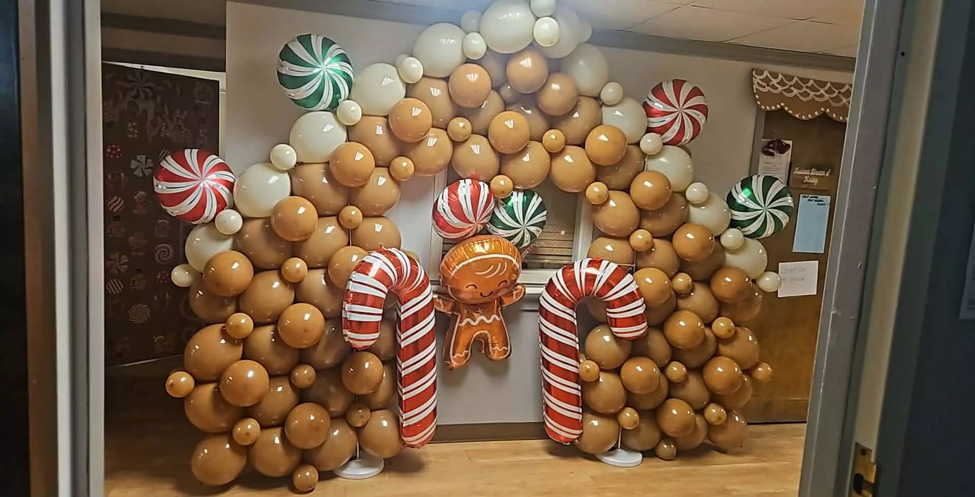 Christmas gingerbread balloon arch with candy cane columns and peppermint foil balloons filling a doorway