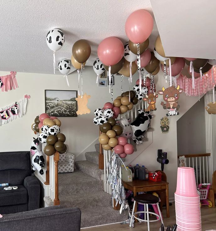 Cow print balloon columns and foil cow balloons lining a staircase at a birthday party
