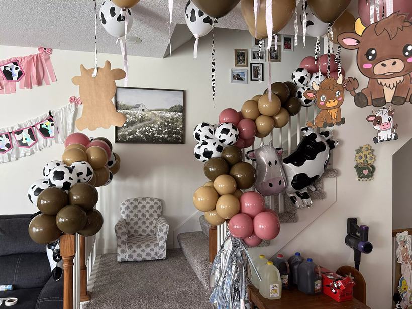 Close up of balloon columns in brown, tan and pink topped with cow print foil balloons in a living room