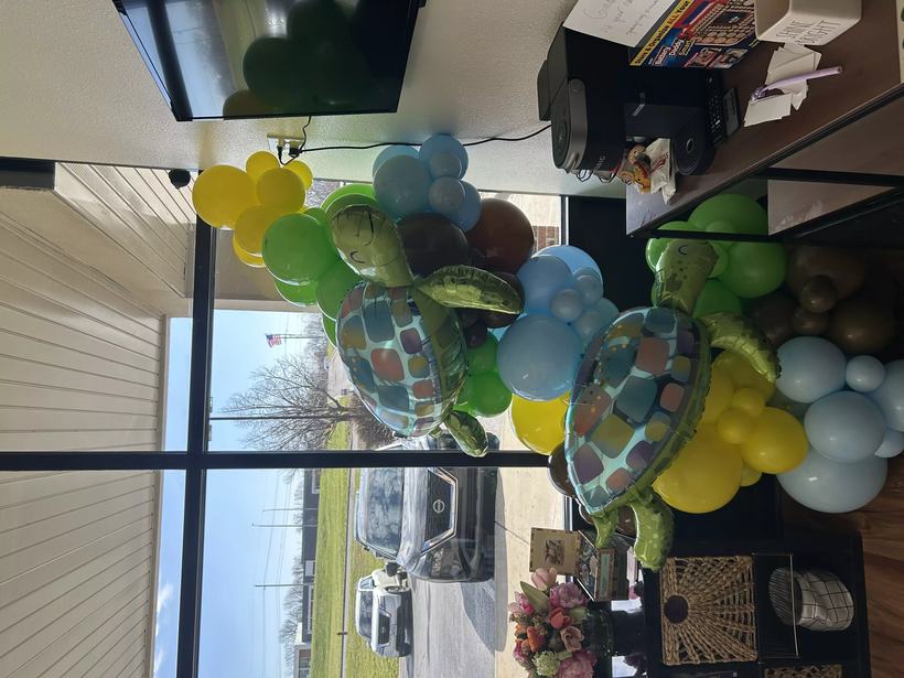 Sea turtle balloon garland in blue, green and yellow seen against a storefront window with the street outside