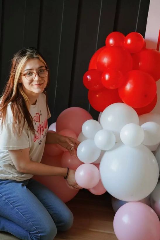 Soleil Burnett attaching balloons while building a red, pink and white Valentine's garland