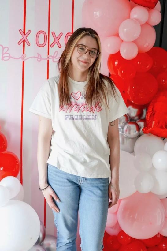 Soleil Burnett standing in front of a finished XOXO Bestie balloon backdrop in red, pink, white and silver