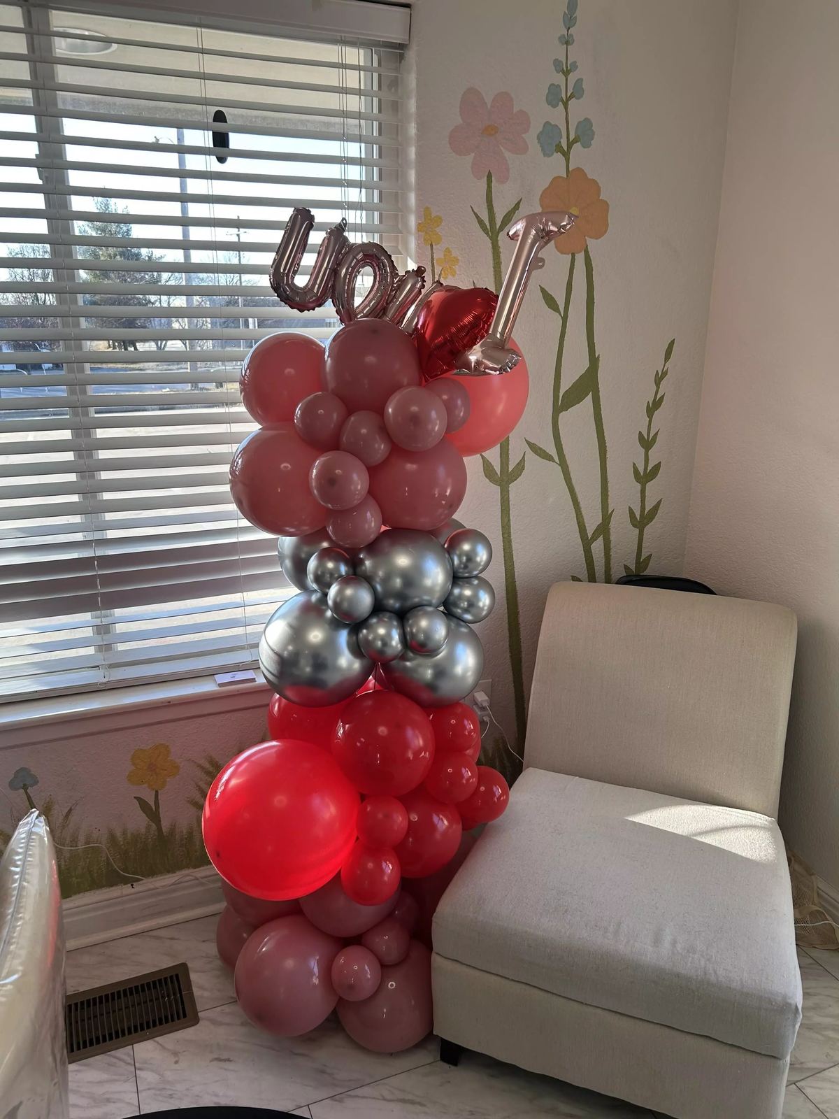 Valentine's balloon garland in deep red, pink and chrome silver mounted on a wall with a foil love script balloon