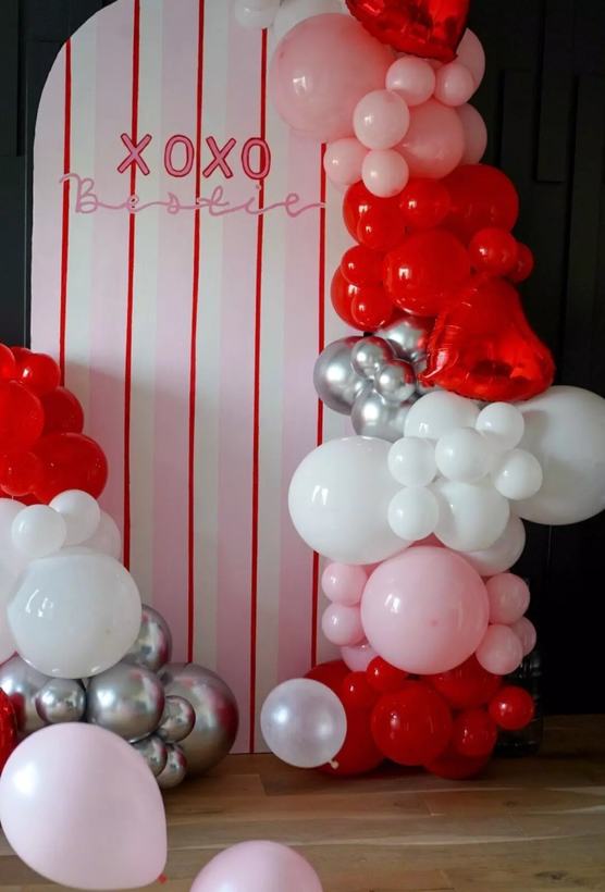 XOXO Bestie striped backdrop with a red, pink, white and silver Valentine's balloon garland