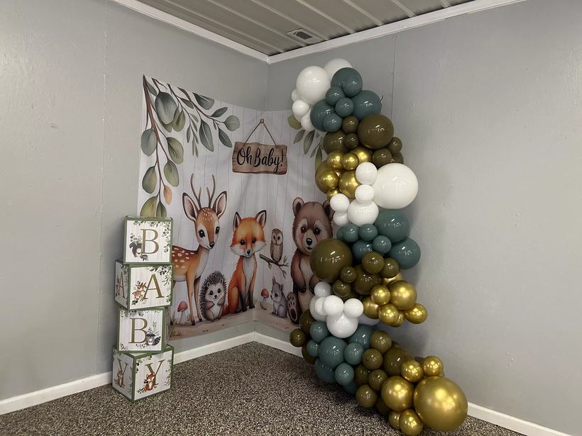 Woodland baby shower balloon garland in sage green, gold and white beside an Oh Baby backdrop